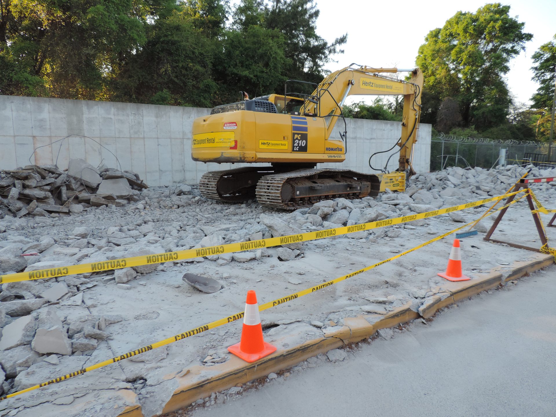 Excavator breaking up a concrete slab on a commercial demolition site