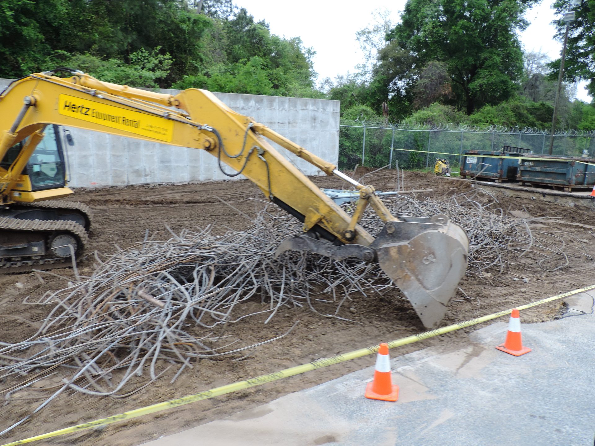 Excavator loading demolition debris into a haul-off pile